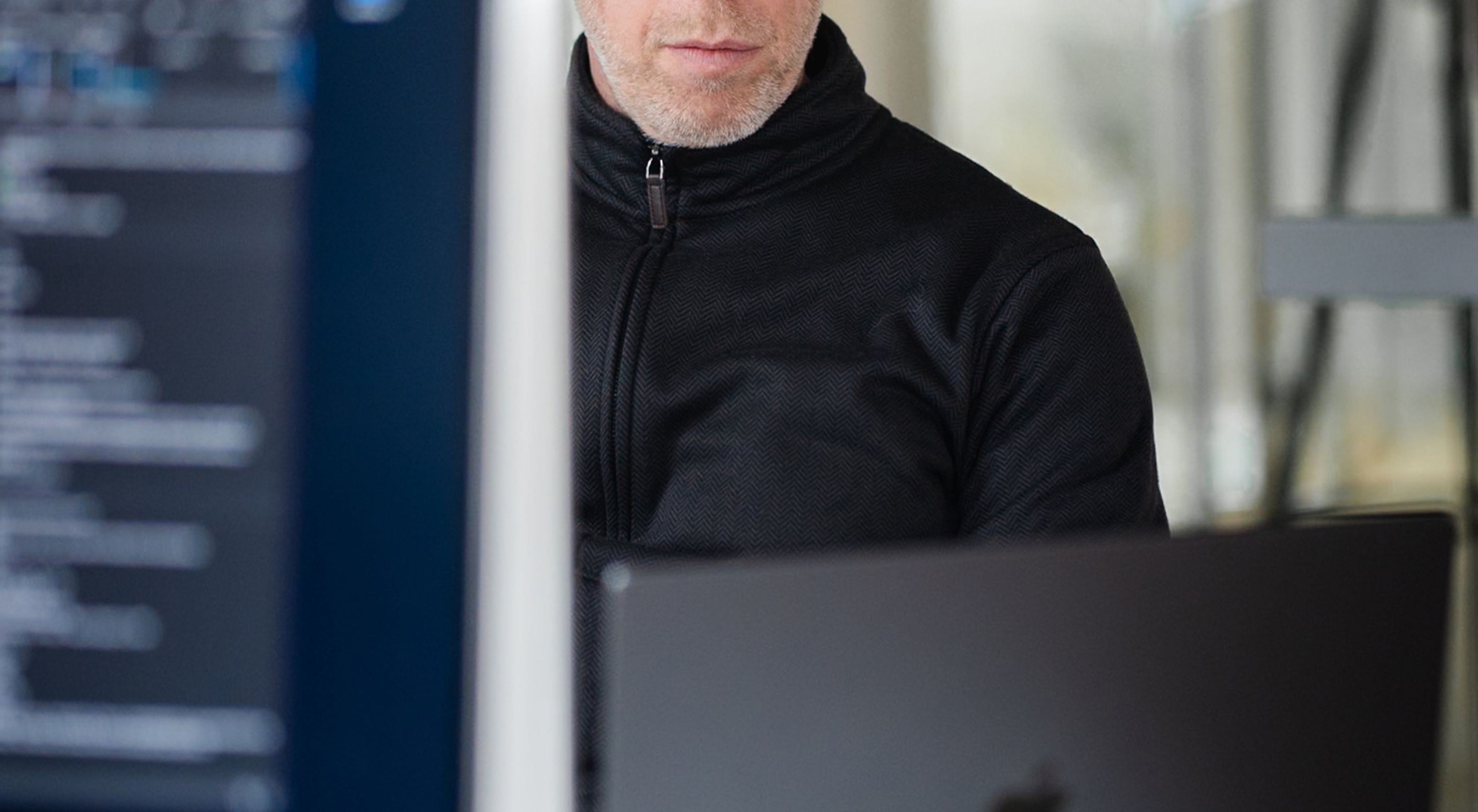 En person med keps med texten pigment arbetar på en laptop i ett modernt kontor.