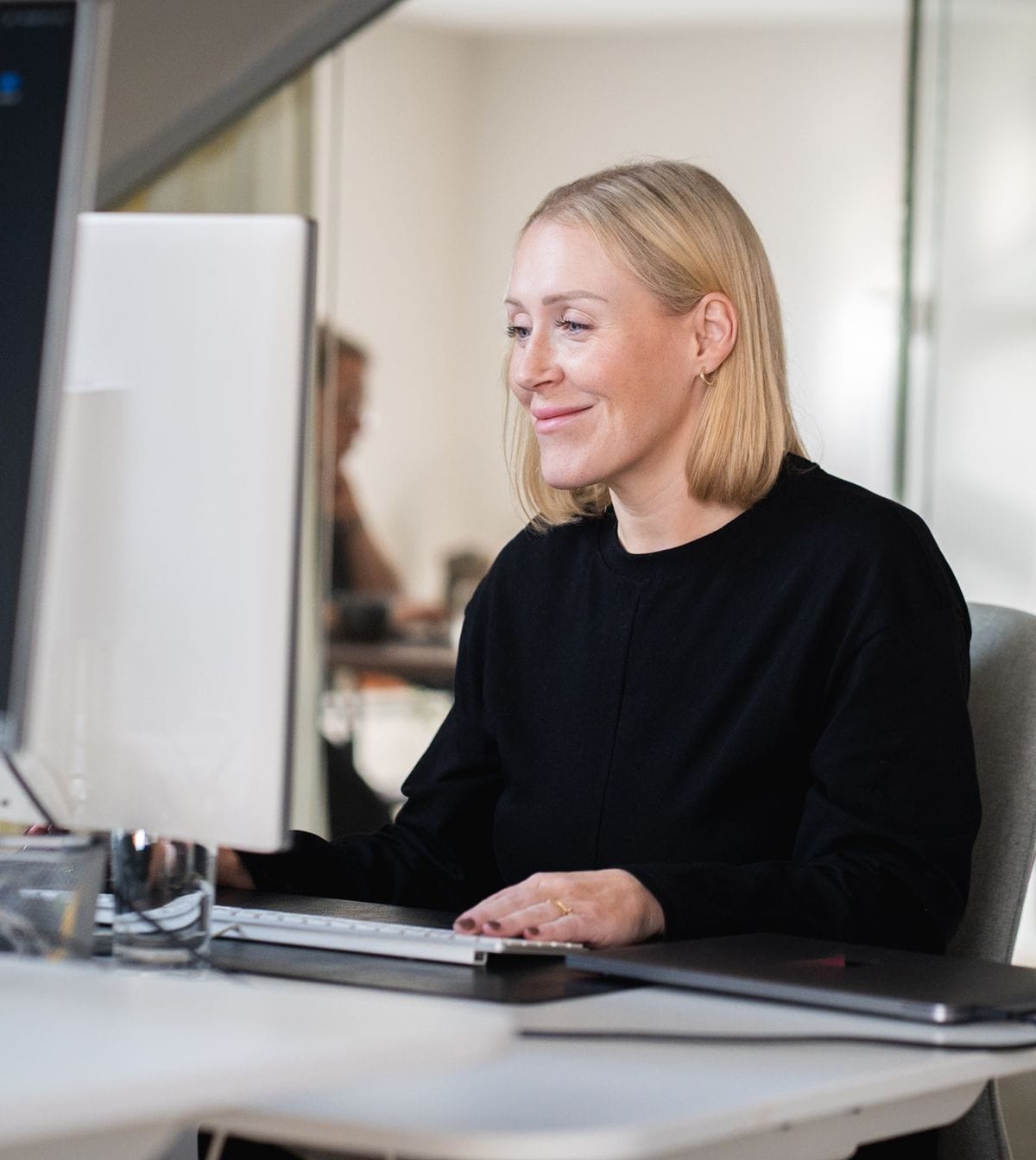 A woman with blonde hair sits at a desk working on a computer at Pigment’s office.