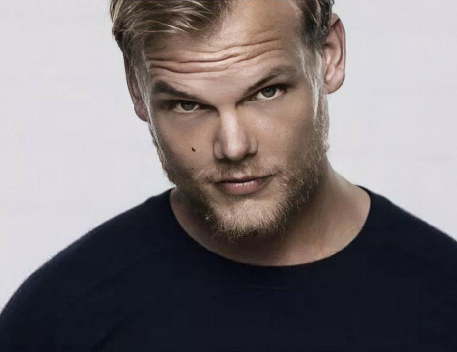 Man med blont hår och skägg som tittar direkt in i kameran, iförd en svart tröja. Neutral bakgrund.