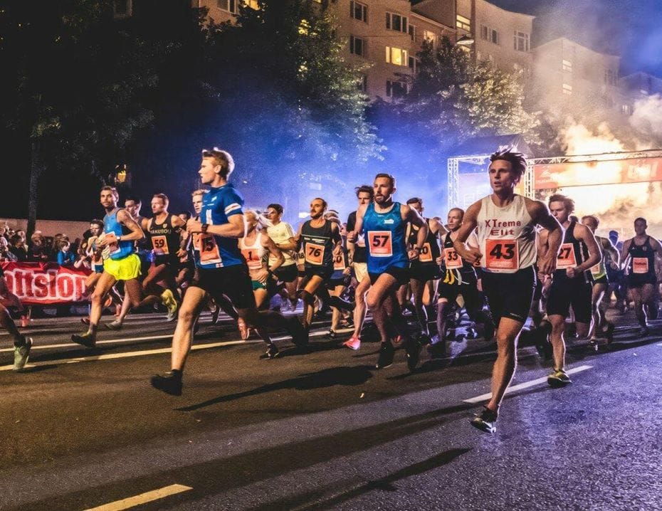 Ett stort antal löpare tävlar i ett kvällslopp på stadsgator, upplysta av starka lampor och omgivna av publik. Det är Midnattsloppet.