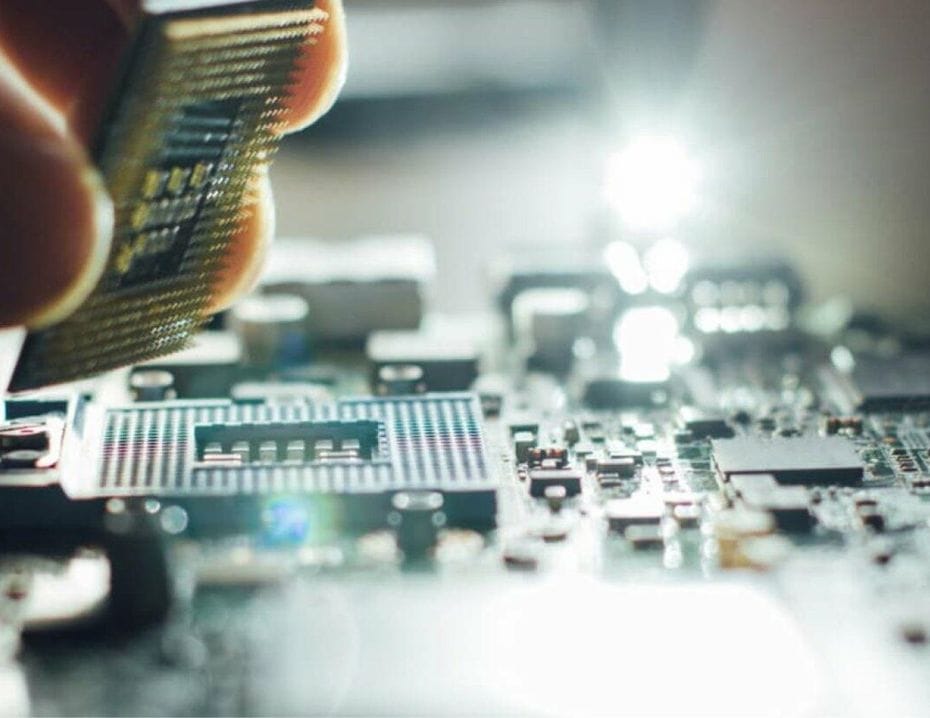 En hand placerar en processor på ett kretskort i ett tekniskt arbetsområde.