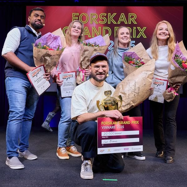 Fem personer på scenen med blommor och ett diplom för Forskar Grand Prix. En man i mitten håller diplomet och en pokal.