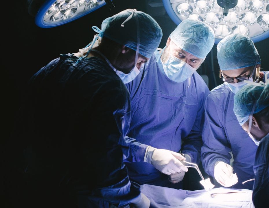 Kirurger i operationssalen fokuserade på en patient under en operation, omgivna av kirurgiska lampor.
